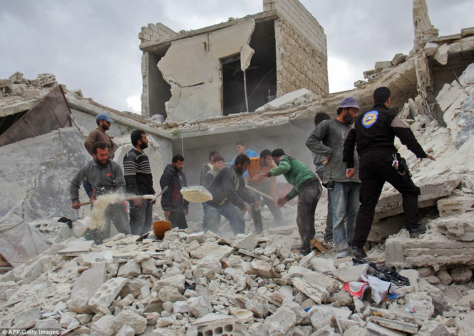 Rescuers and civilians inspect a destroyed building in the Syrian village of Kfar Jales, on the outskirts of Idlib, following air strikes by Syrian and Russian warplanes on November 16