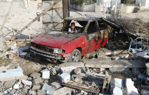 A Palestinian boy sits inside a car dest