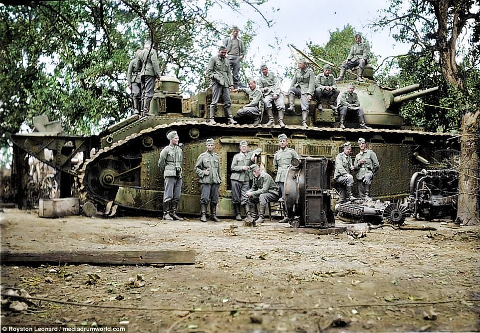 Seventeen German soldiers stand in front of and on top of a massive tank as they pose up for a propaganda photograph which became a strong tool during the Second World War. The armoured vehicle is surrounded by machinery and weapons, likely to be trying to paint a picture of the Nazi strength despite their inevitable slide into surrender