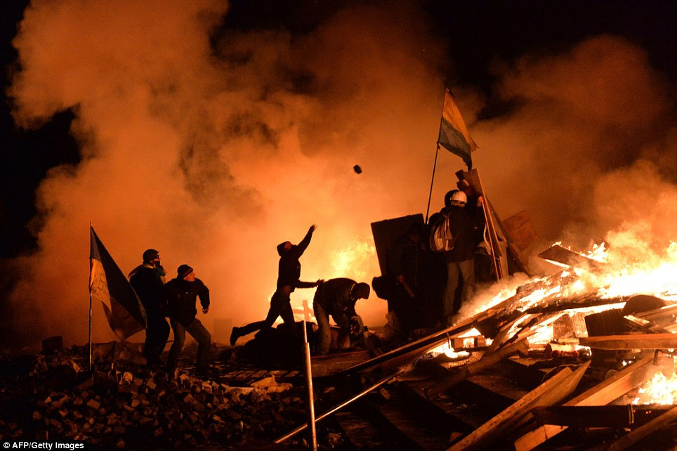 Violent confrontation: Protesters positioned amongst burning debris throw cobblestones as they clash with the police