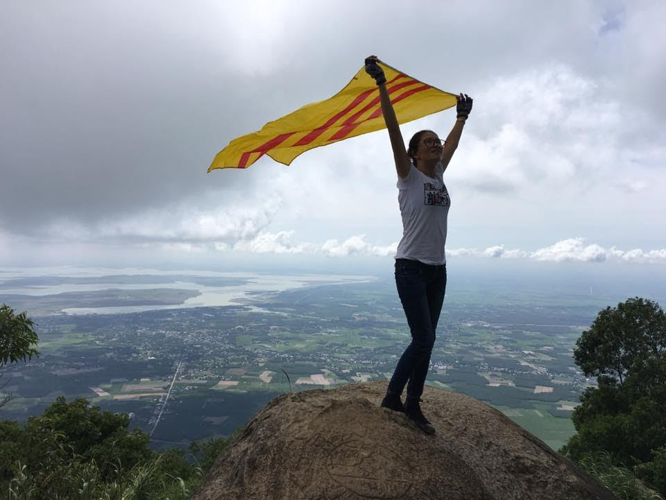 Một cô gái với lá cờ ba sọc đỏ tung bay trên đỉnh núi (ảnh; Facebook Hong Thai Hoang)