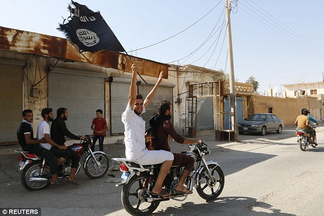 Captured: A resident of Tabqa waves the Islamic State flag on Sunday after militants seized the nearby air base