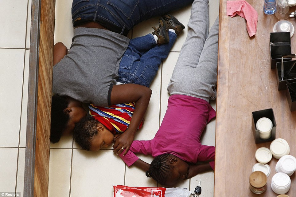 Protection: A mother and her children lie on the floor as they attempt to hide while the gunmen armed with automatic weapons go on the rampage