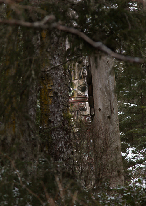 totem face through trees, Totems Historic District, Kasaan, Alaska