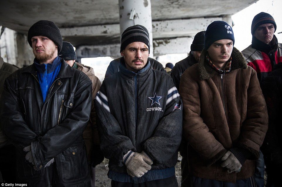Ukrainian prisoners of war are lined up by rebels before they are ordered to begin sifting through the rubble
