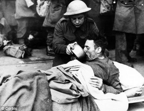 Rescue: A British soldier helps a wounded man drink while waiting to be evacuated from Dunkirk