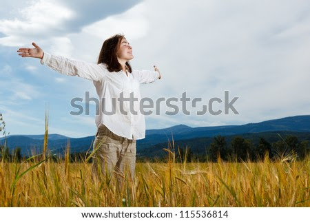 Girl holding arms up against blue sky - stock photo