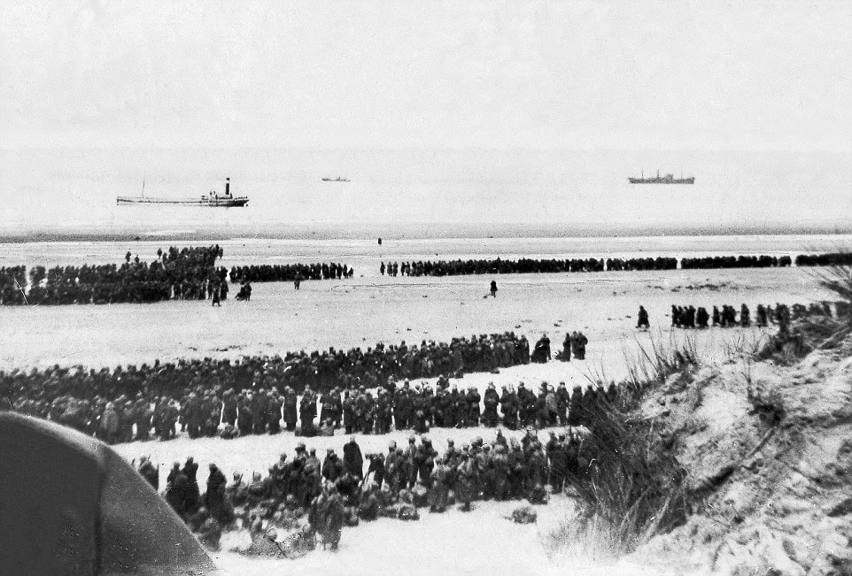 Troops wait in an orderly fashion on the beaches of Dunkirk for their turn to be rescued. In the distance, some of the ships sent to save them