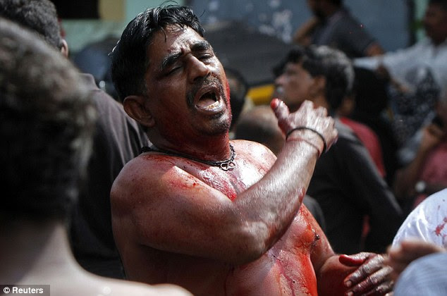 A Shiite Muslim whose face and torso is covered in blood, beats his chest 