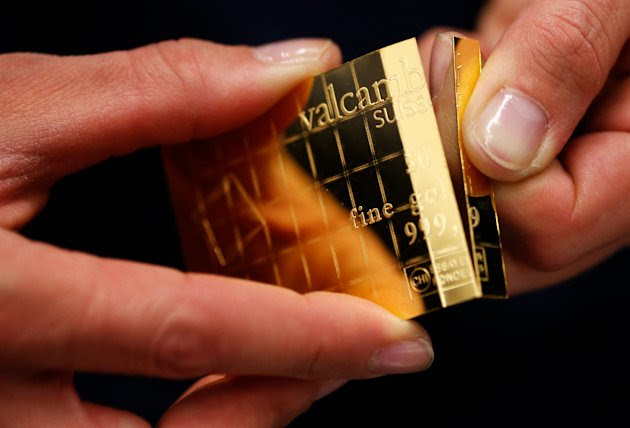 An employee shows dividing a gold Combibar at a plant of gold refiner and bar manufacturer Valcambi SA in the southern Swiss town of Balerna