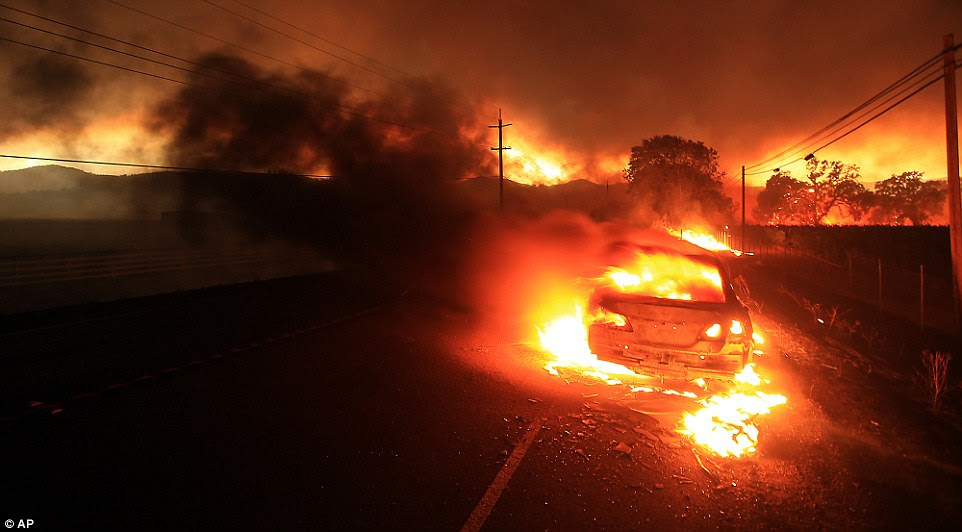 A car is engulfed in flames as the Valley fire spots over Highway 29 near Middletown