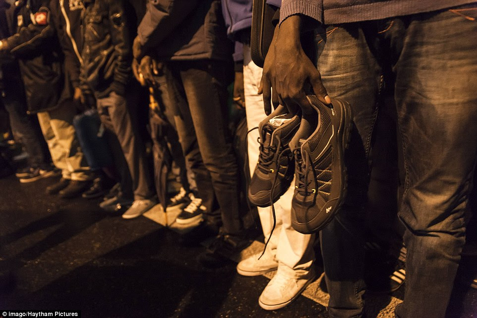 A migrant is seen holding a spare pair of shoes as he waits to board a bus evacuating him from one of the illegal tent camps