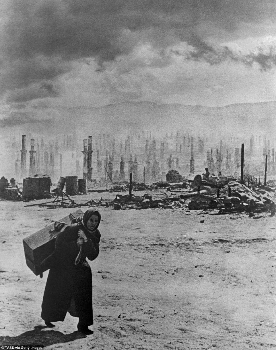 A view of Murmansk destroyed by the Nazi bombers after they launched an offensive against the city in 1941, as a woman flees carrying a suitcase