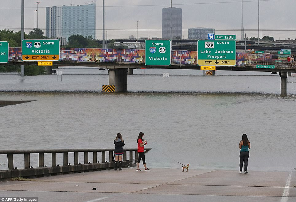 The colorful bridges above highway 59 towered over a bleak scene on Sunday (right), with large portions of the road under water