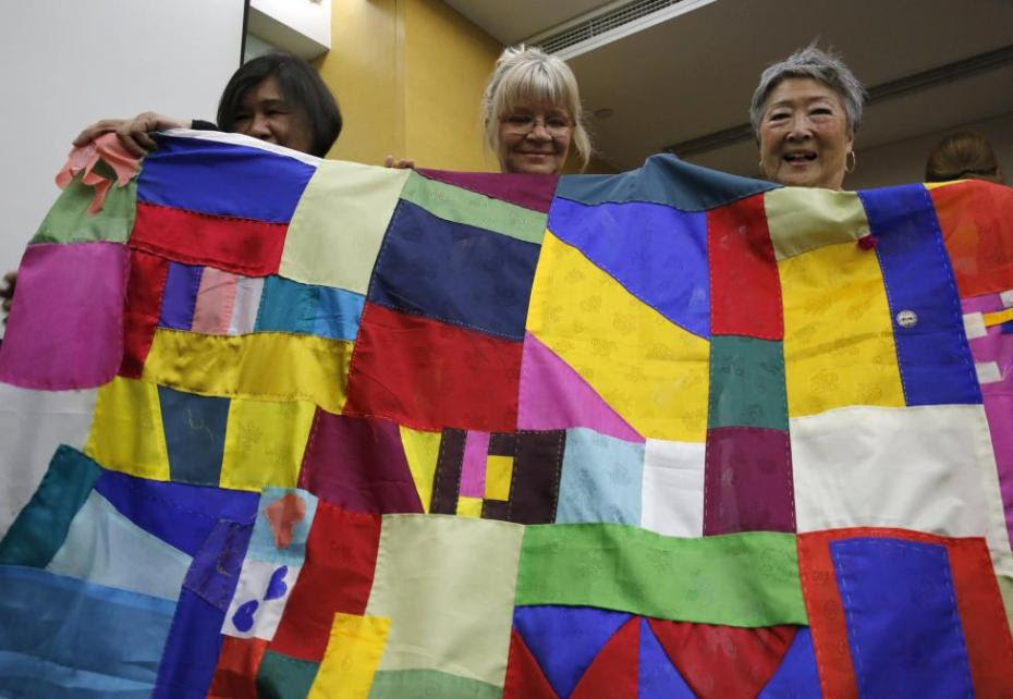 NGO activist Choi Ai-young (R) and other members of the WomenCrossDMZ group pose with Korea's traditional patchwork before the group leaves for North Korea's capital Pyongyang, at a hotel in Beijing, China, May 19, 2015. REUTERS/Kim Kyung-Hoon