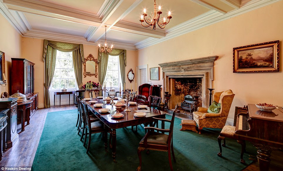 The spacious dining room has more than enough room for the whole family; gets bathed in light from two large windows, and features a huge carved fireplace