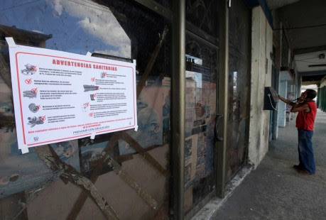 A health warning is seen on a wall as a man talks by public phone in Havana