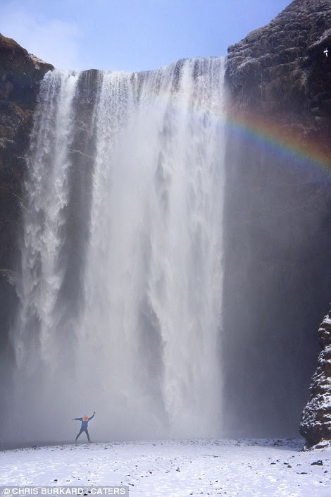 A rainbow appears through the mist of an Arctic waterfall 