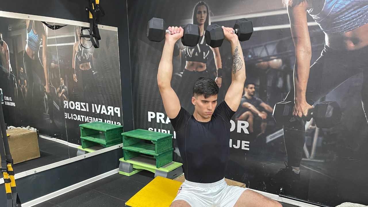 Vanja performs a dumbbell shoulder press.