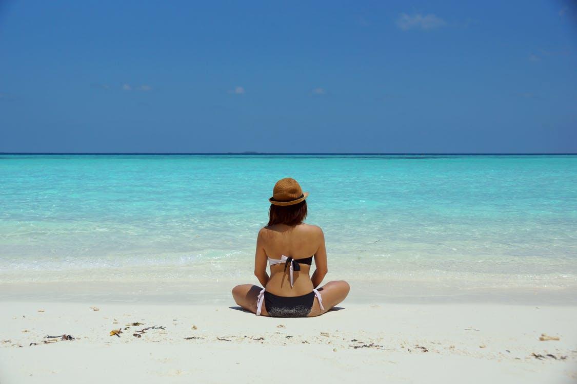 Free Woman Wearing Black and White Brassiere Sitting on White Sand Stock Photo