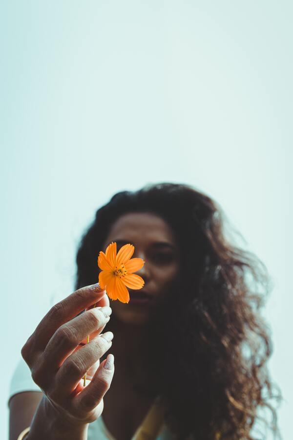 Mulher segurando uma flor na mão 