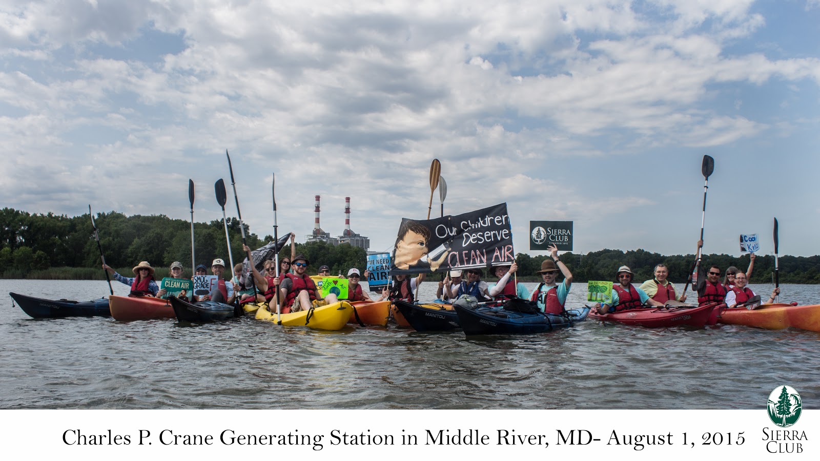 Activists sit in kayaks and raise their oars