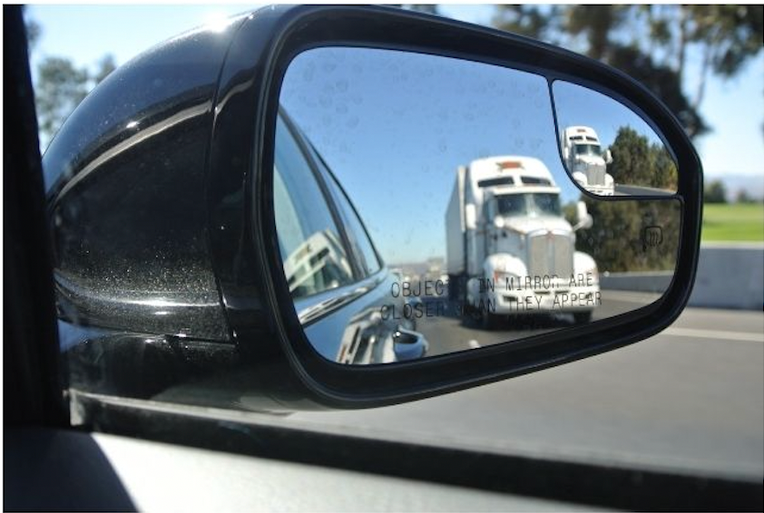 the view of a truck in a cars rearview mirror