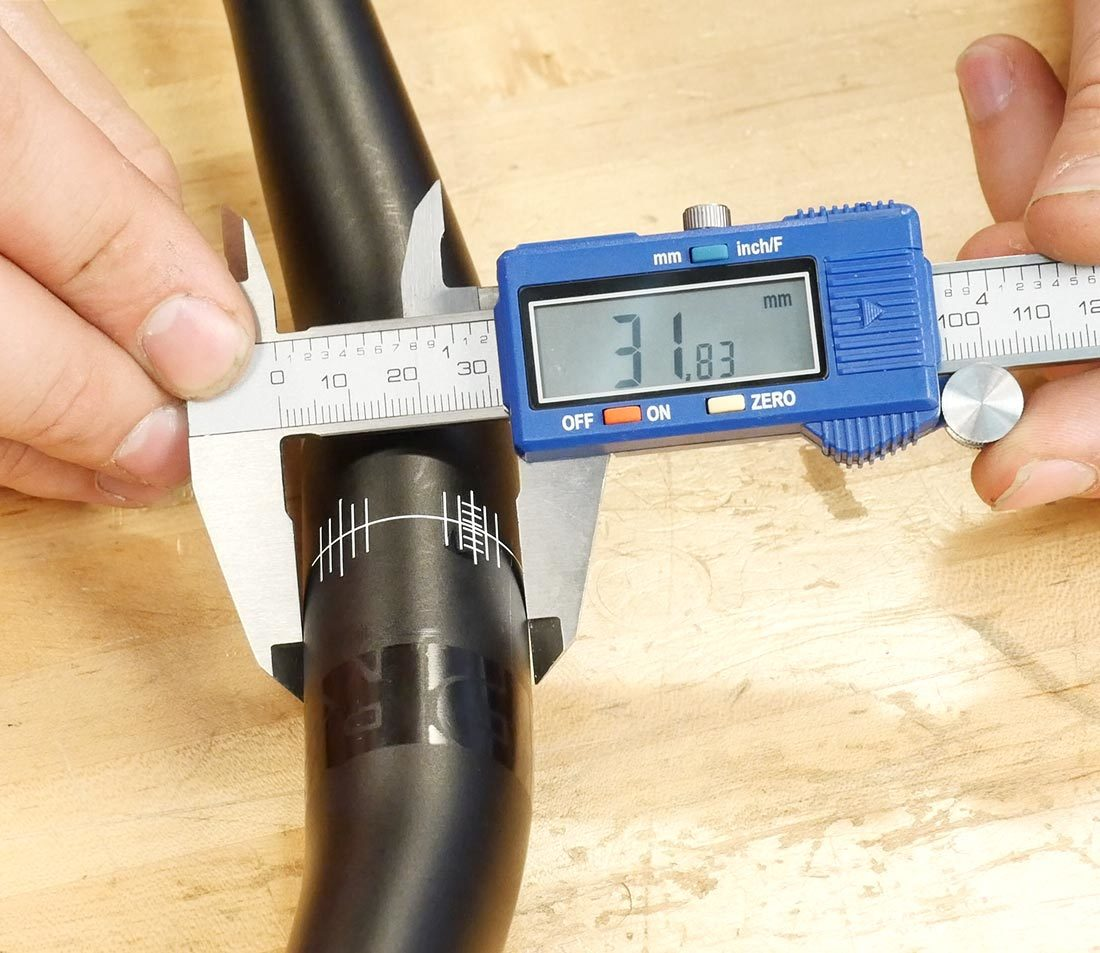 Measure the handlebar clamp diameter of a mountain bike by placing the widest area of the clamp inside the caliper’s jaw.