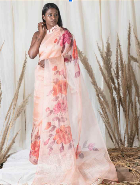 A woman draped into a peach organza handpainted saree with floral print