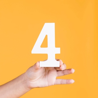 Woman's hand holding up the number 4 against an yellow background