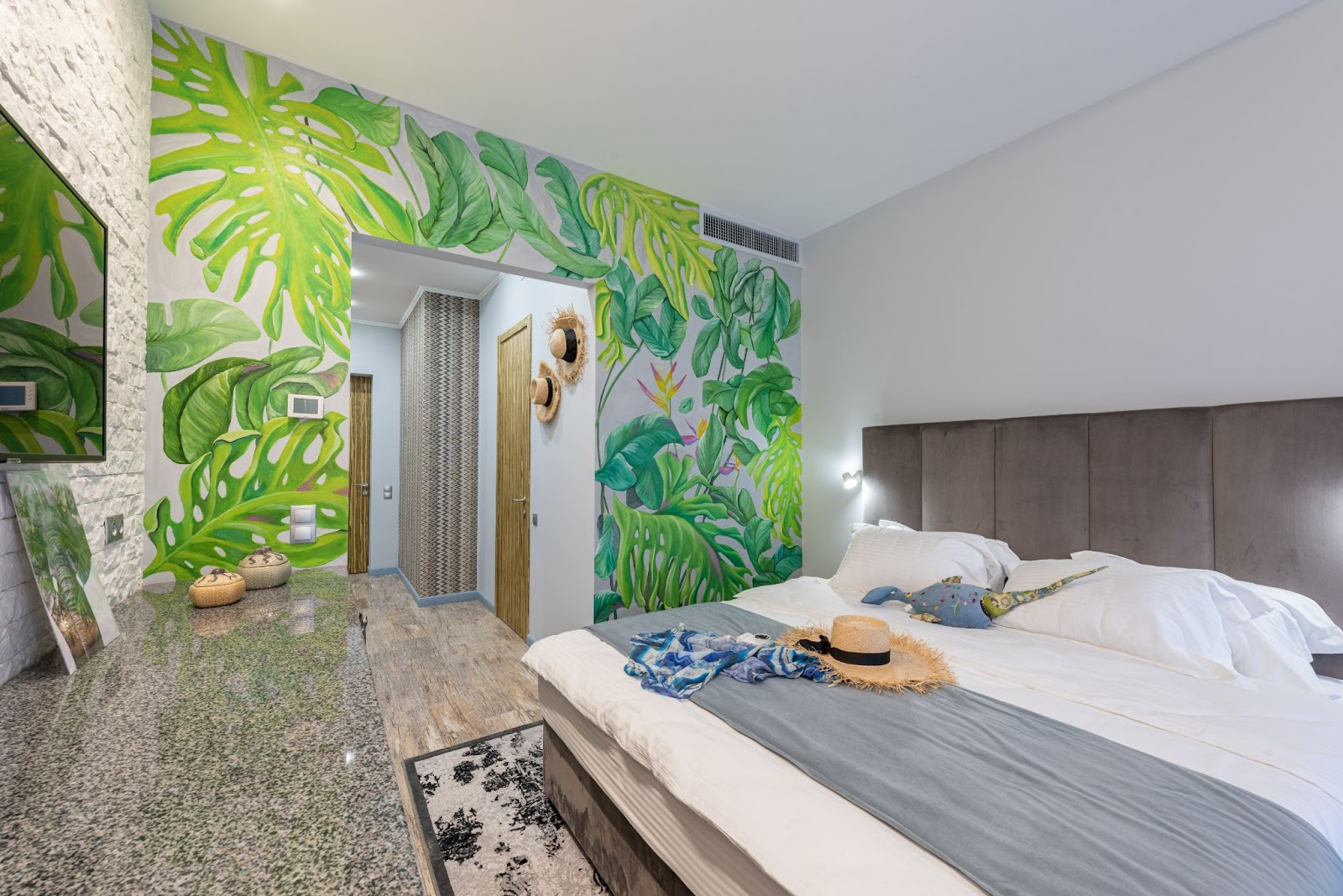 Bold wallpaper design full of greenery on one wall of the bedroom