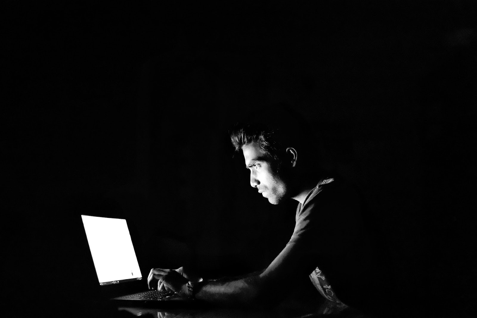 Man looking at the computer in the dark app downloads dropping
