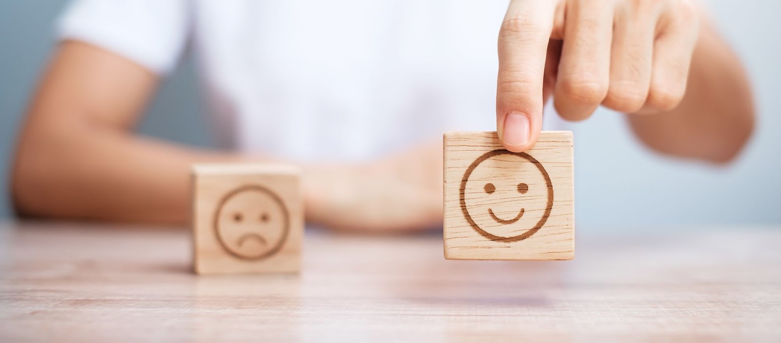 Two blocks of wood with happy and sad smiley faces, representing positive and negative sentiment