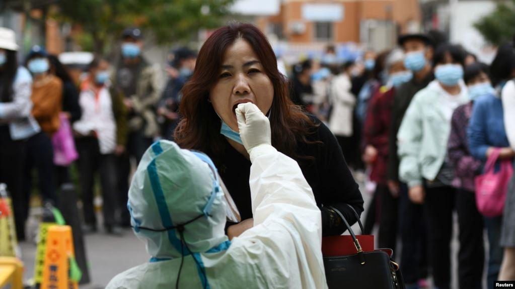中国青岛的医护人员正在给一名妇女做核酸检测。(2020年10月13日)