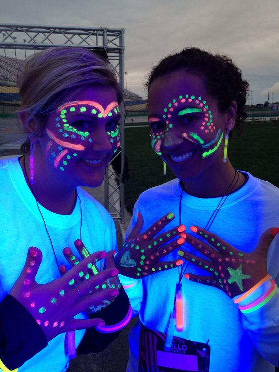 Two women wearing glow-in-the-dark stickers or beads.
