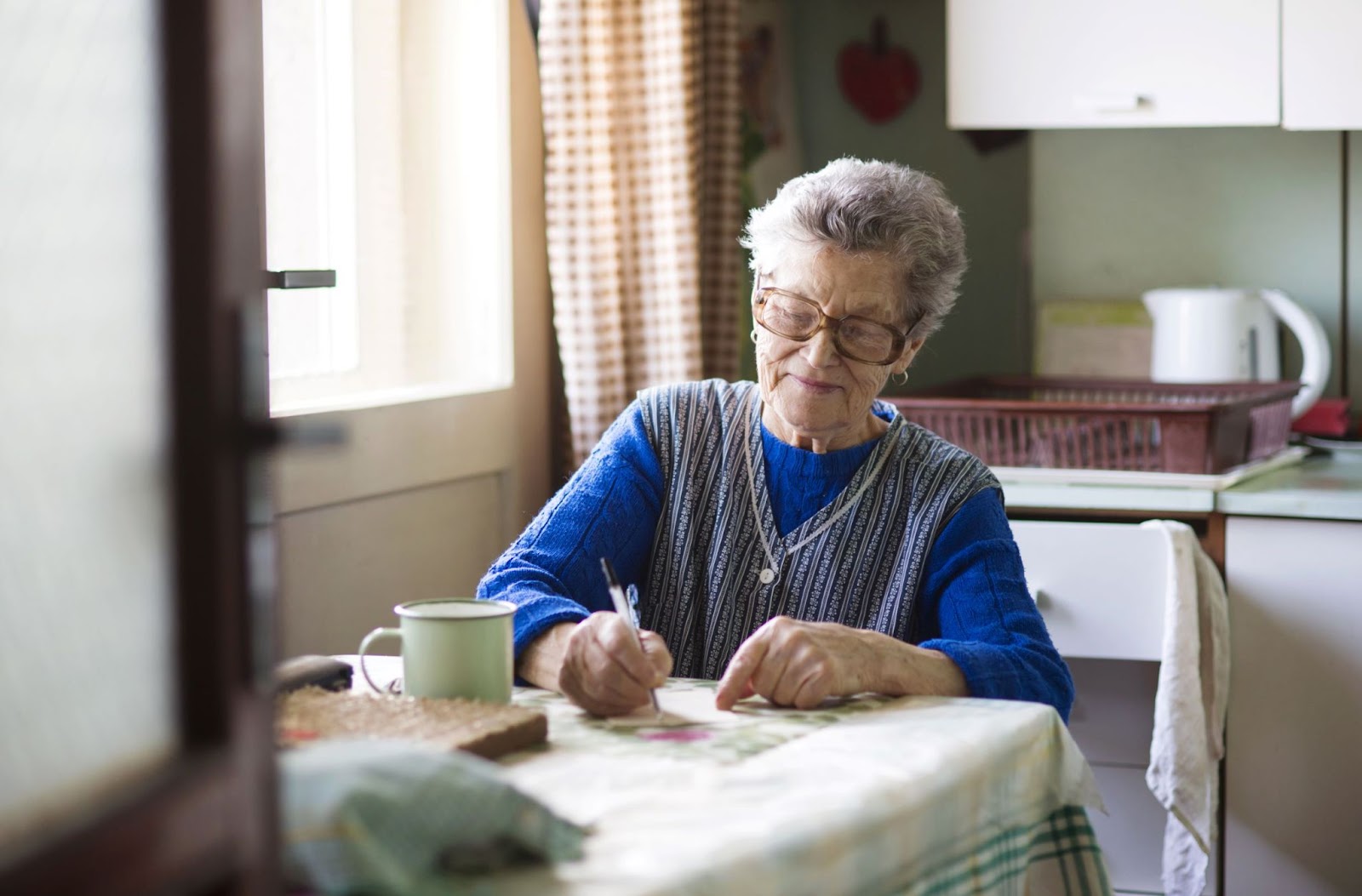 older-woman-writing-in-her-kitchen