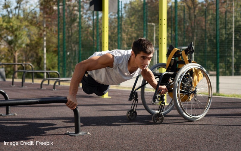 Person using their wheelchair to do pushups in an outdoor setting