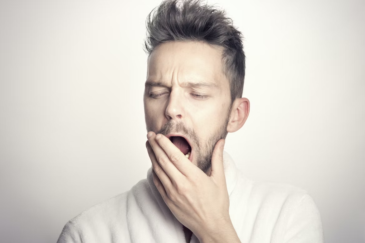 man covering mouth to yawn, slump, sluggish, tired, fatigue