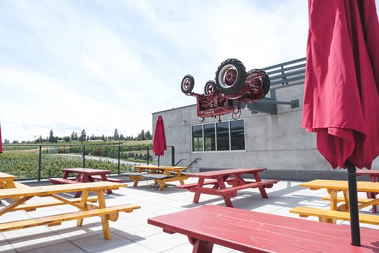 upside cider outdoor patio with red and orange tables and an upside down tractor as decor.