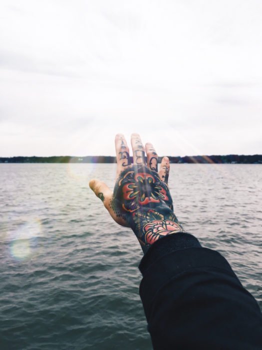 mano tatuada posa frente al mar