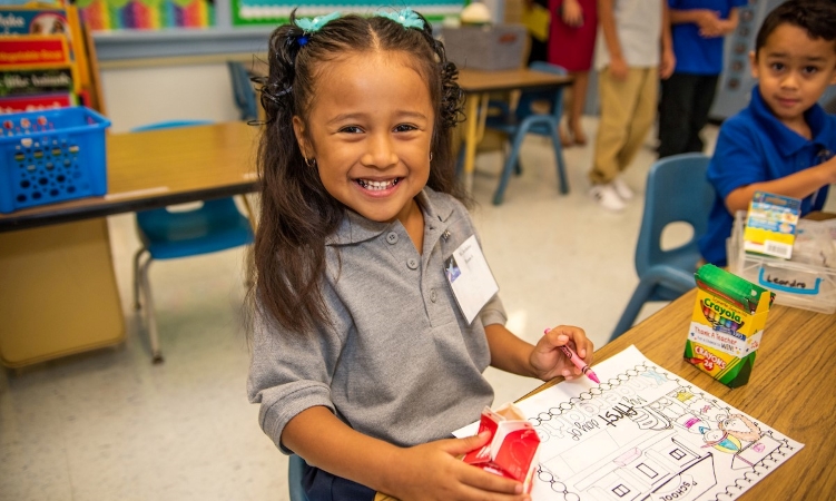 A young student in Houston, Texas, smiles while coloring at school.