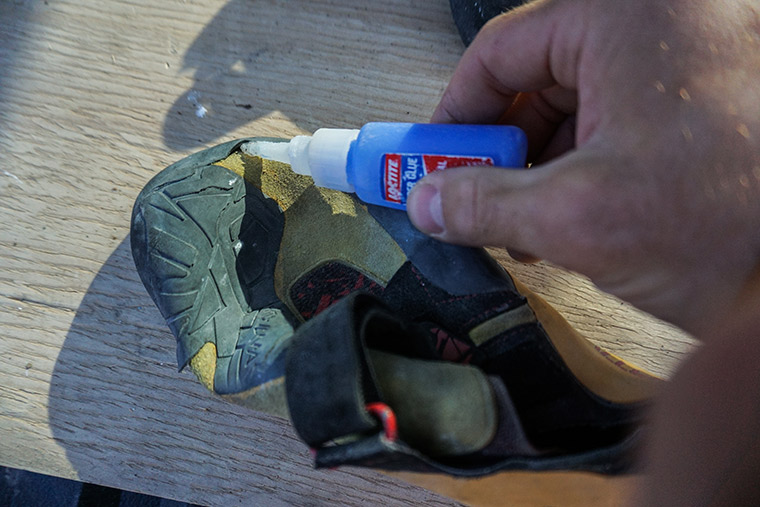 Applying superglue to a climbing shoe to reattach the rubber