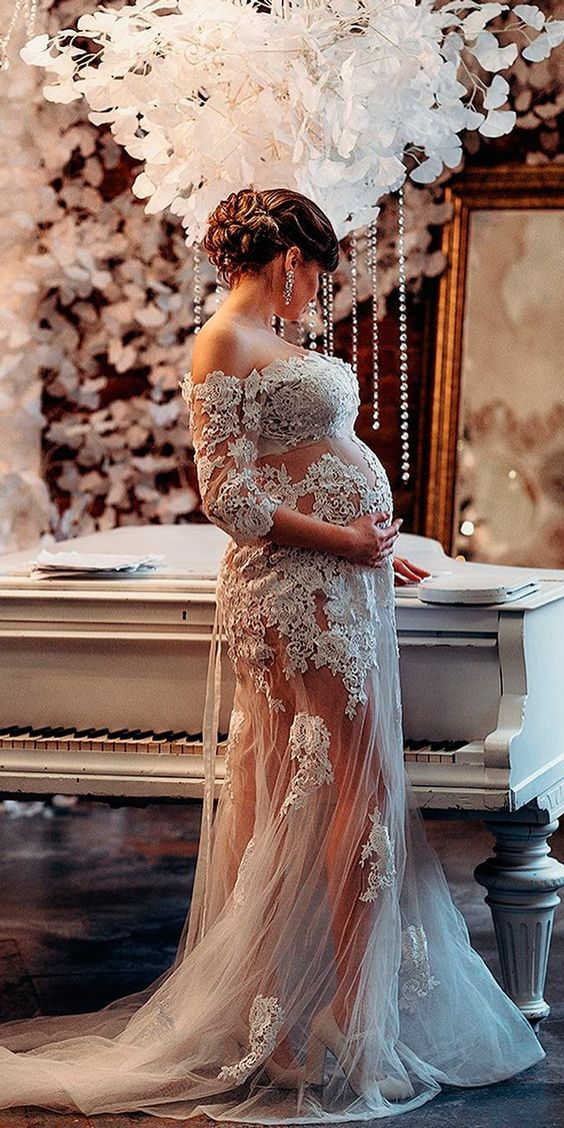 A lady wearing a sheer tulle maternity wedding dress