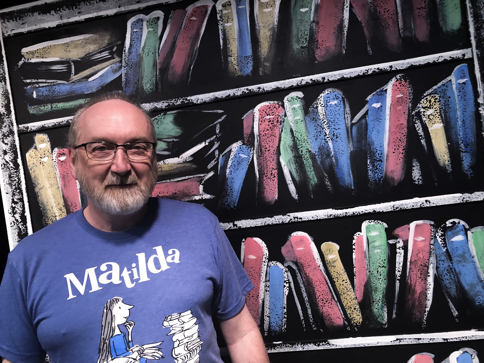 Michael Flowers, Director of Red Mountain Theatre Company's Matilda The Musical, stands by bookcase prop