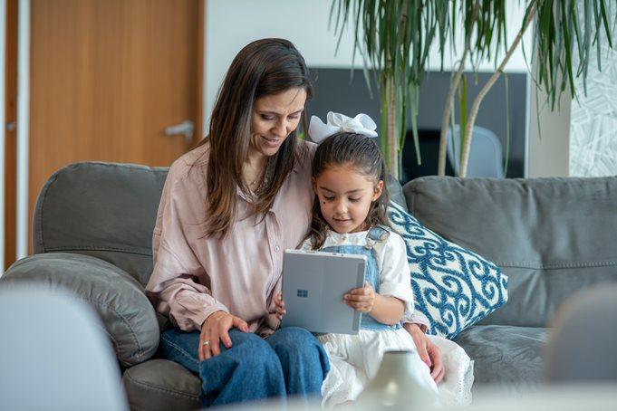 A person and a child sitting on a couch looking at a computer

Description automatically generated with medium confidence