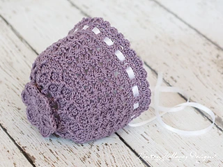 beautiful lacy lavender bonnet lying on white wooden background