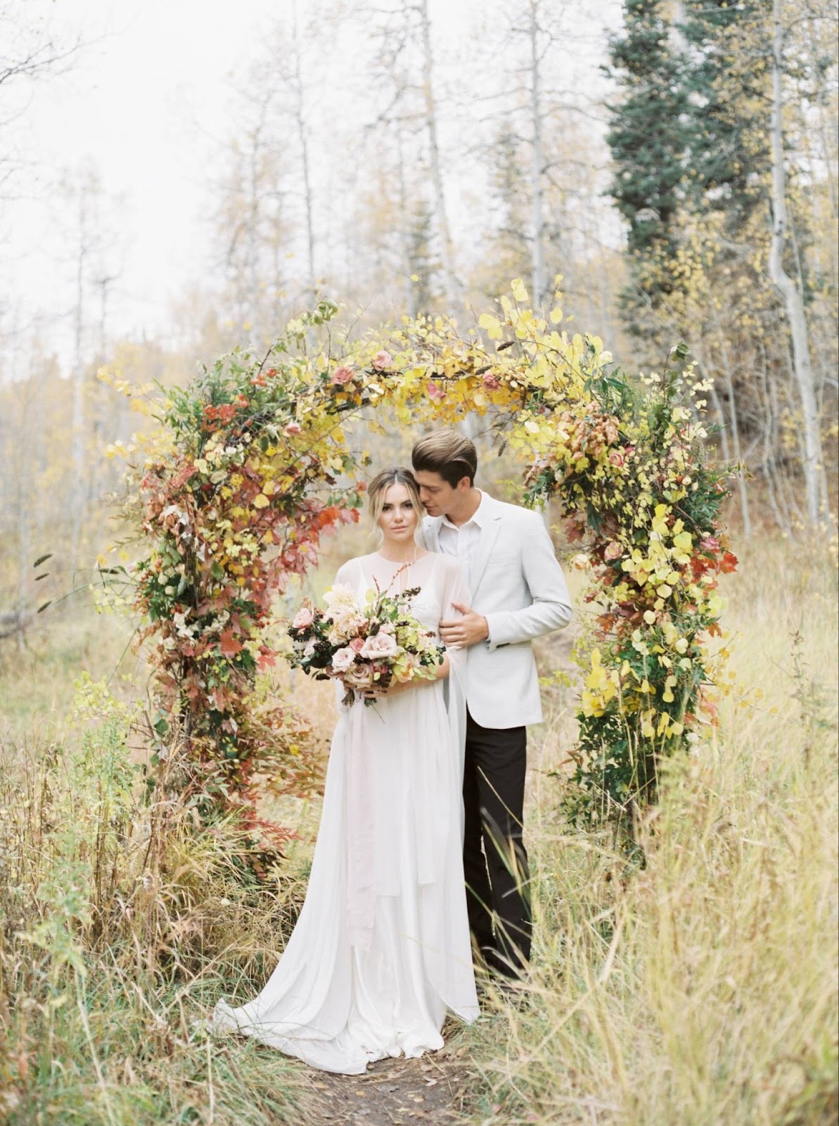 photo of bride and groom with whimsical floral arch