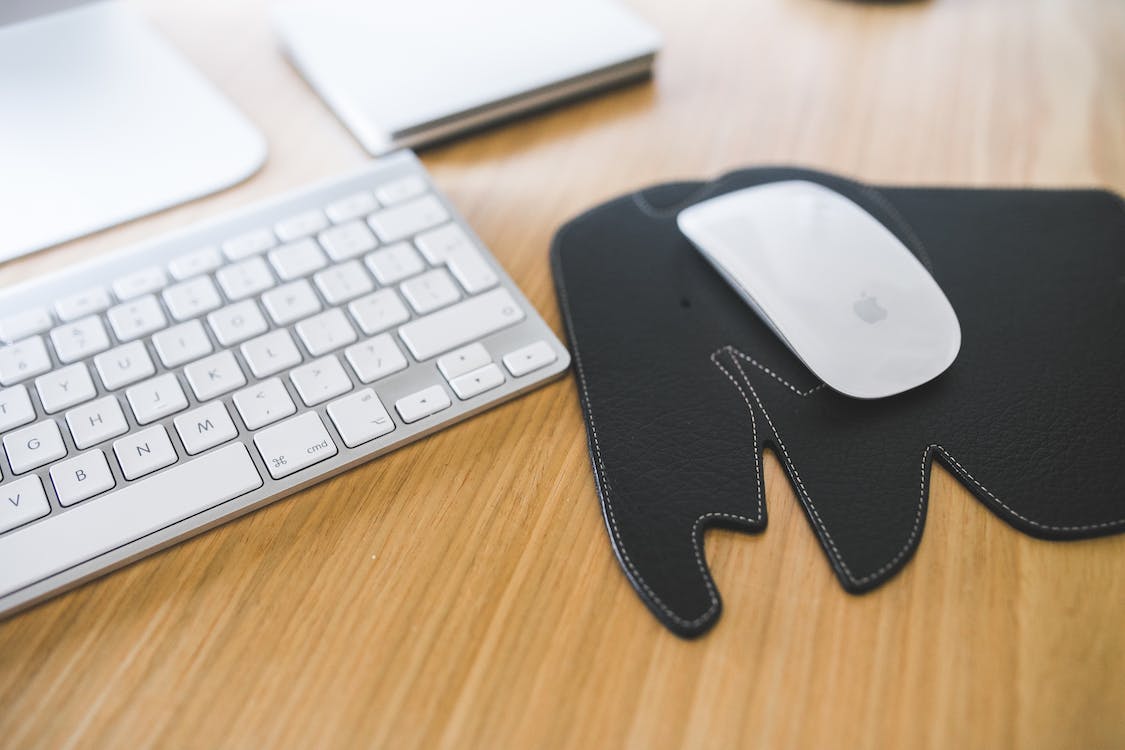 Free White Apple mouse and keyboard on the black Elephant Pad Stock Photo