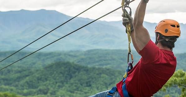 Man in red shirt looking at mountains while ziplining