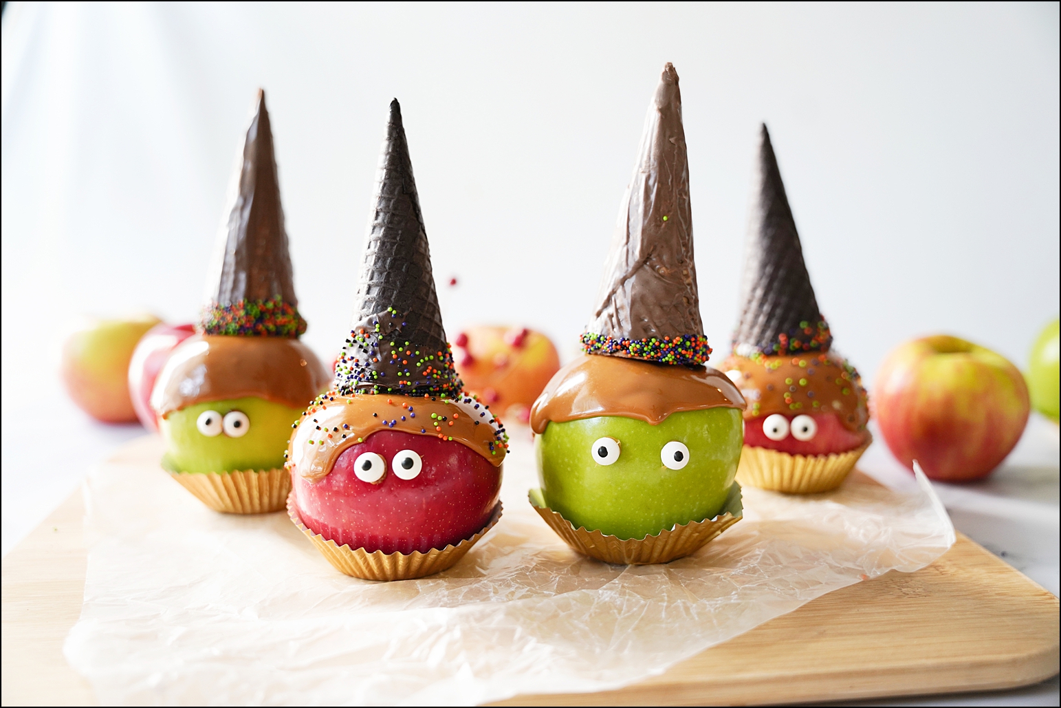 red and green apples that look like they are wearing witch hats